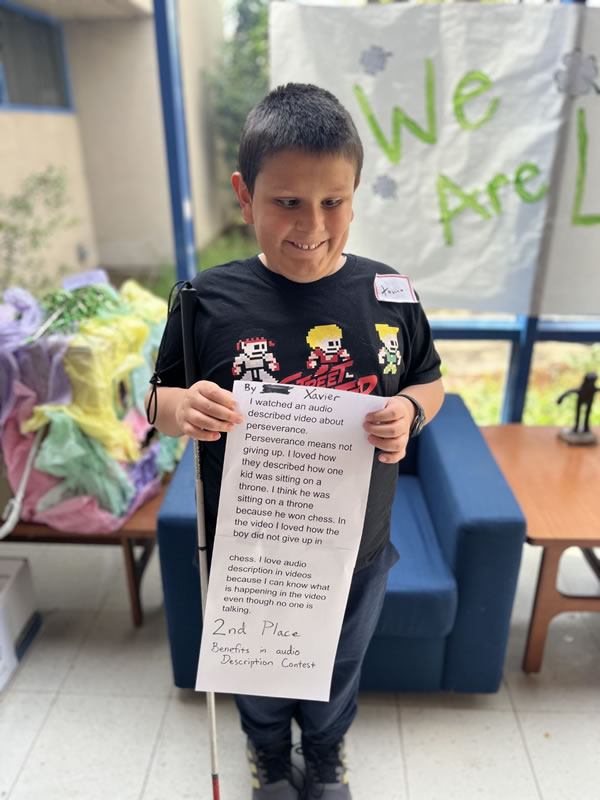 A student holding his printed essay winning second place for a contest.