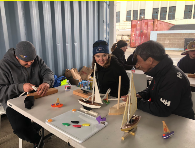 Students creating boats made out of wood, having a good time.